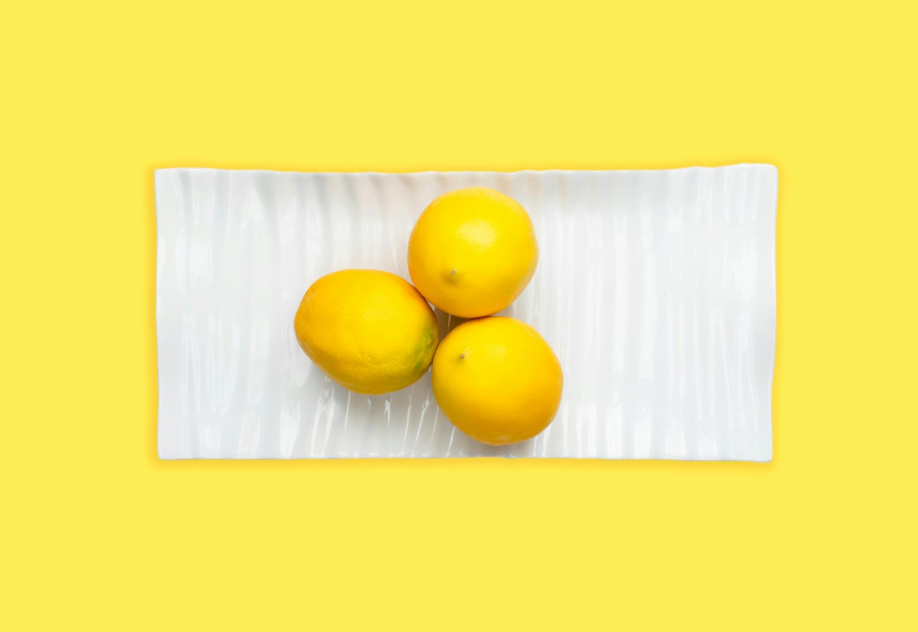 Una mano che tiene un limone fresco contro uno sfondo giallo vivido, che rappresenta comunicazione aperta e piacere consapevole