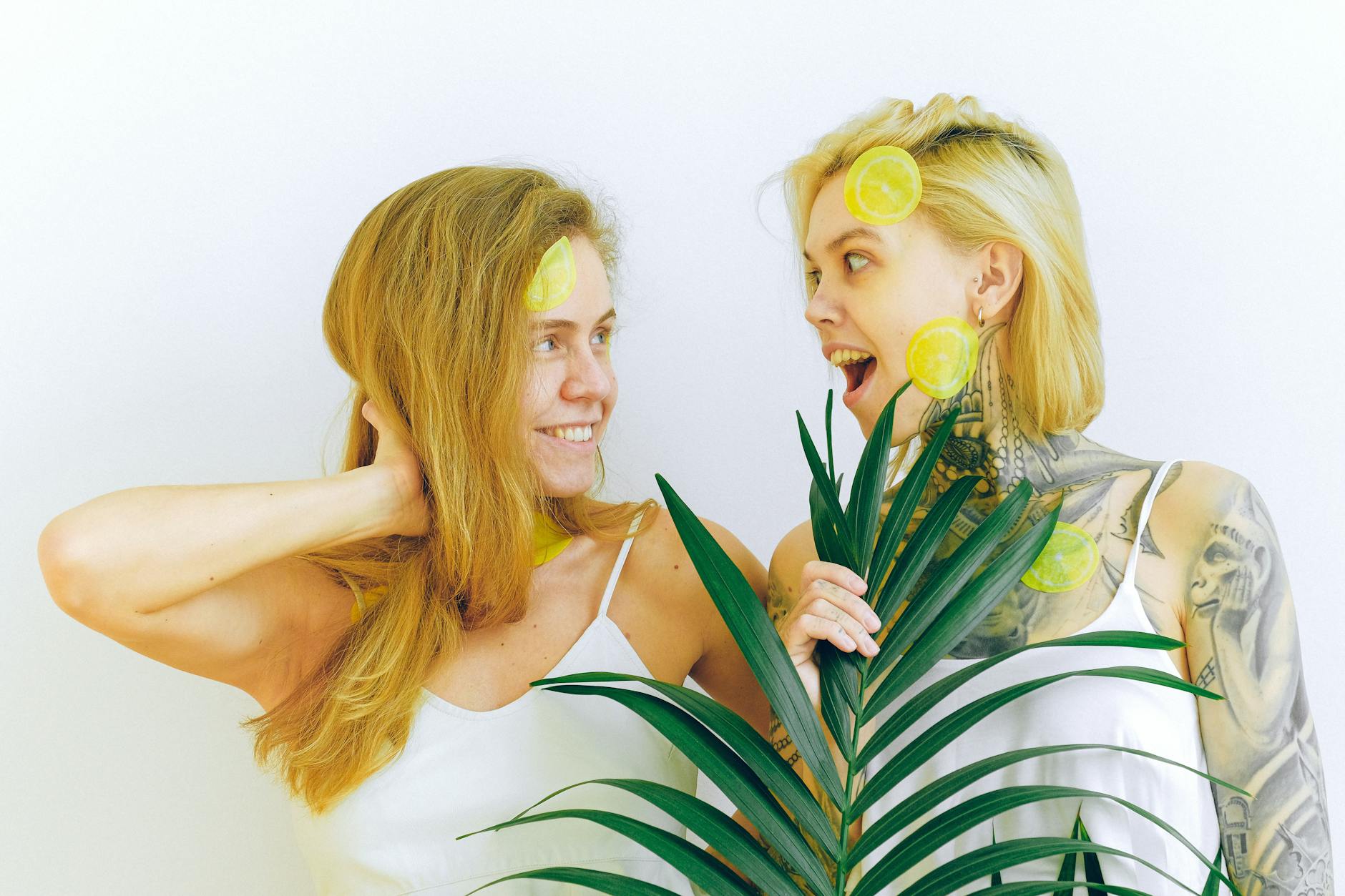 Due donne che sorridono con fette di limone, esprimendo gioia e sensualità in un ambiente intimo
