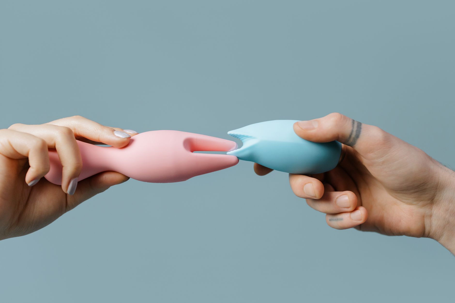 Hands holding pastel-colored silicone toys in a supportive, comfortable way.