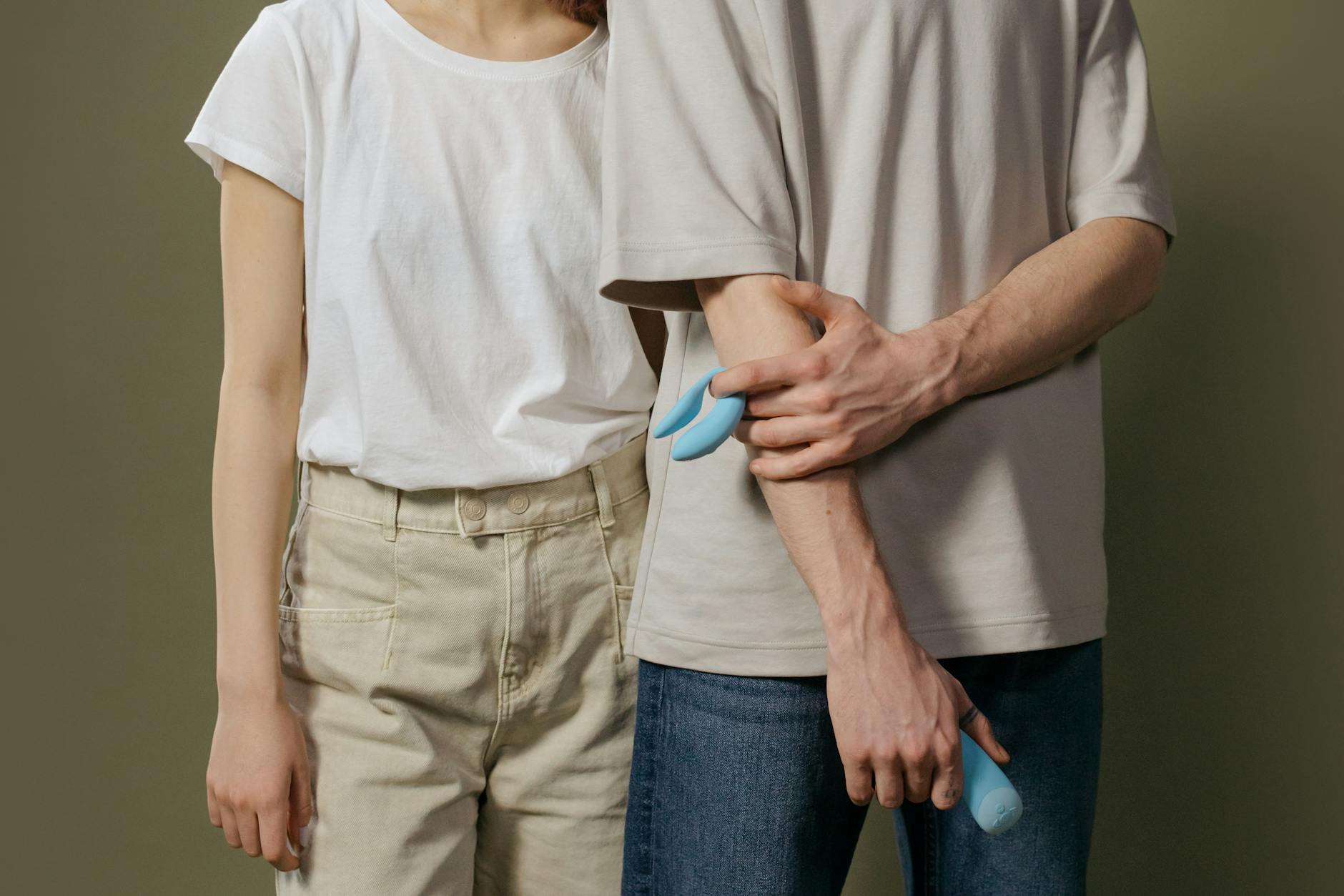 Due mani che tengono insieme un elegante vibratore blu su sfondo viola, simbolo di intimità condivisa e piacere